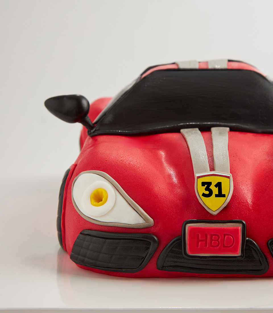 Front view of red Ferrari-style birthday cake with fondant detailing and number 31 badge.