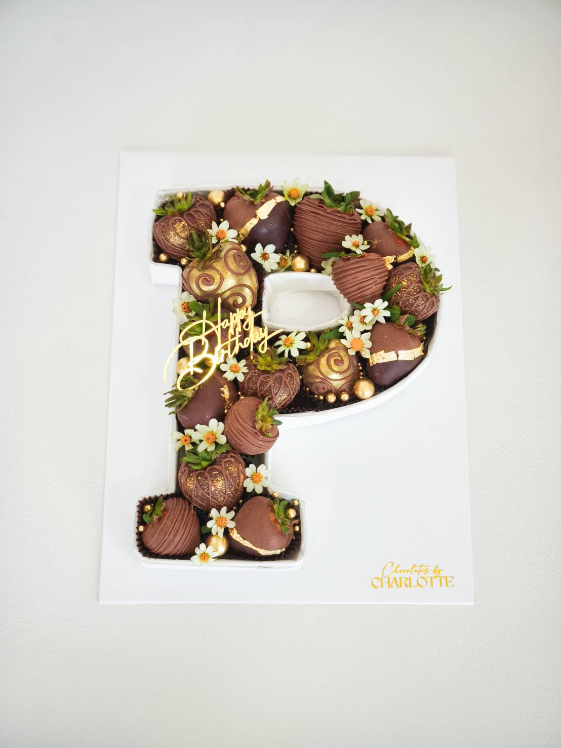 Letter P gift box filled with luxury chocolate-dipped strawberries, gold accents, and fresh floral decorations.