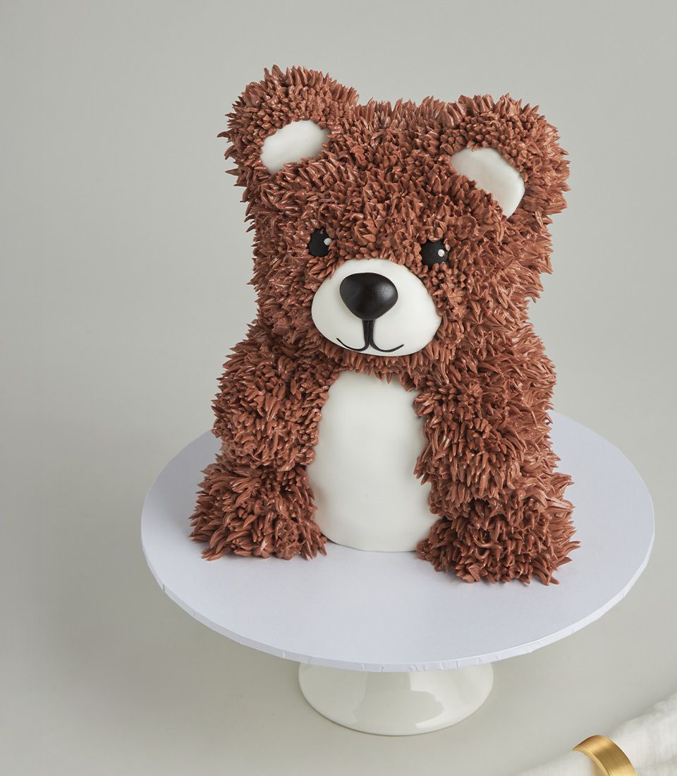 3D teddy bear cake with vanilla sponge base, fondant icing face and body, and piped chocolate-coloured fur details.