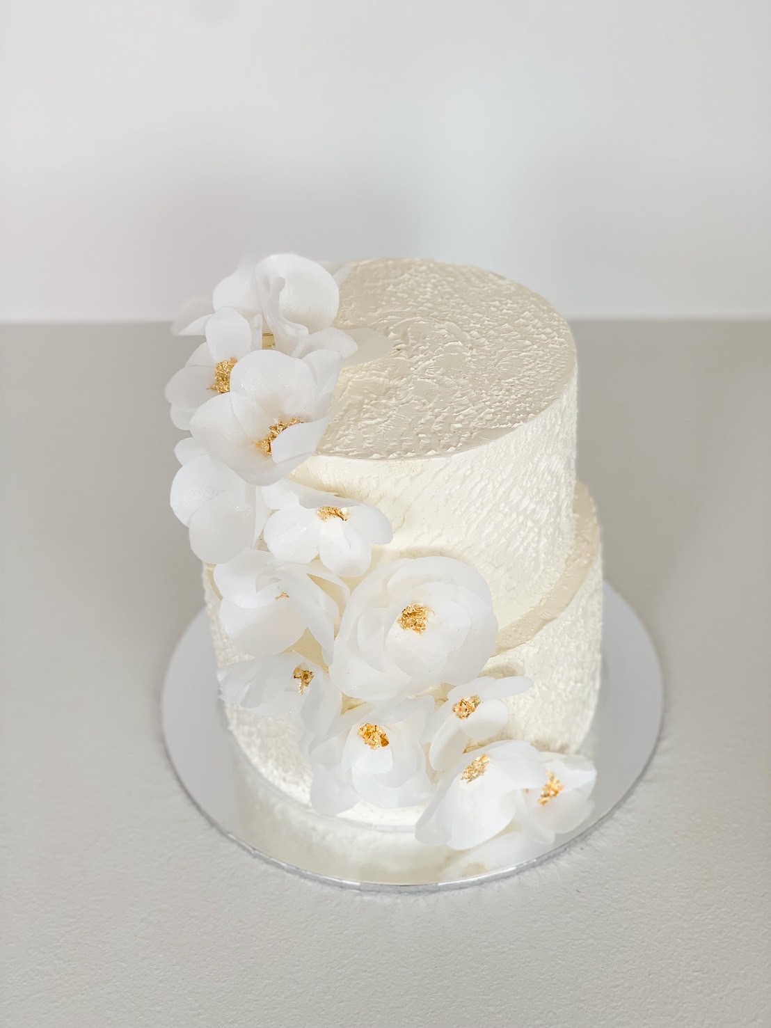 White textured wedding cake with cascading sugar orchids and gold centres