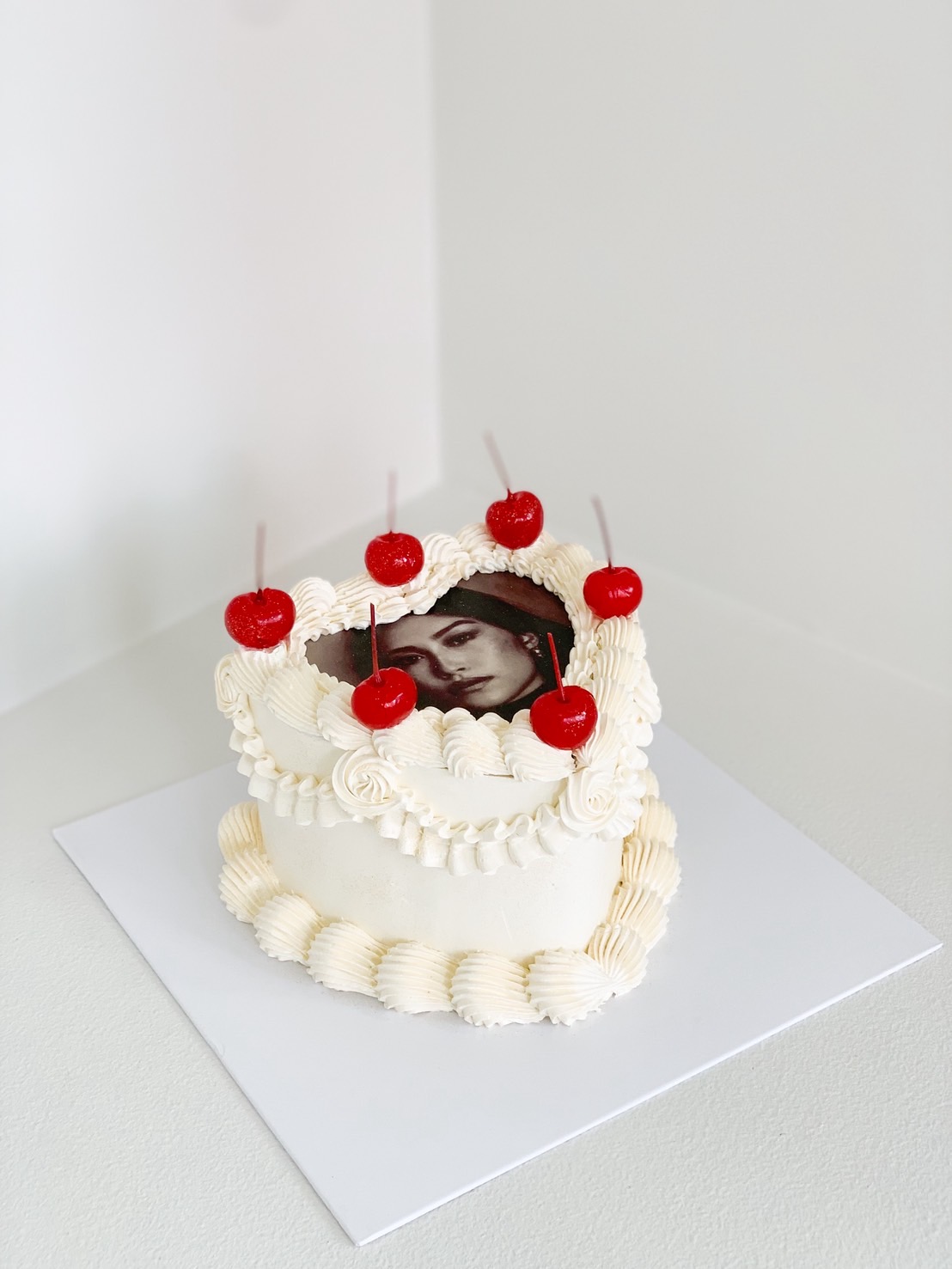Retro-style heart cake with printed photo, piped cream, and red cherries on top
