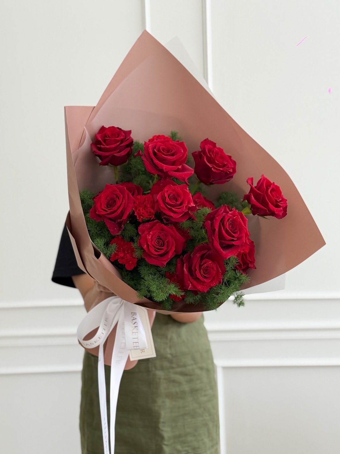 Elegant bouquet of classic red roses wrapped in brown paper with greenery accents and satin ribbon, luxury flower delivery Bangkok