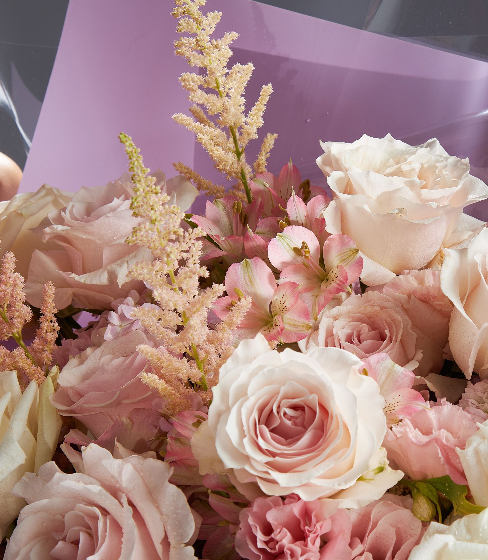 A luxury bouquet of Plya Blance and Pink Cloud Ecuadorian roses with pastel blooms in purple, pink, and cream tones.