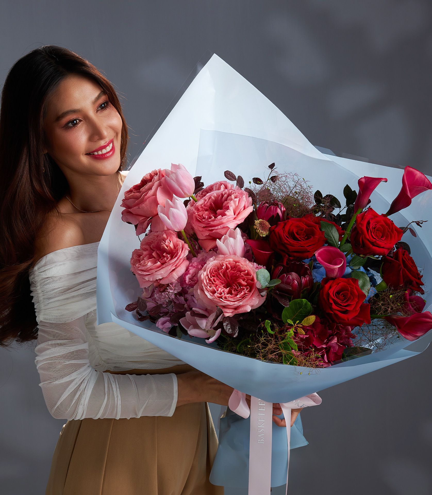 Elegant bouquet of Ecuadorian pink and red roses with tulips, protea, and dark foliage.