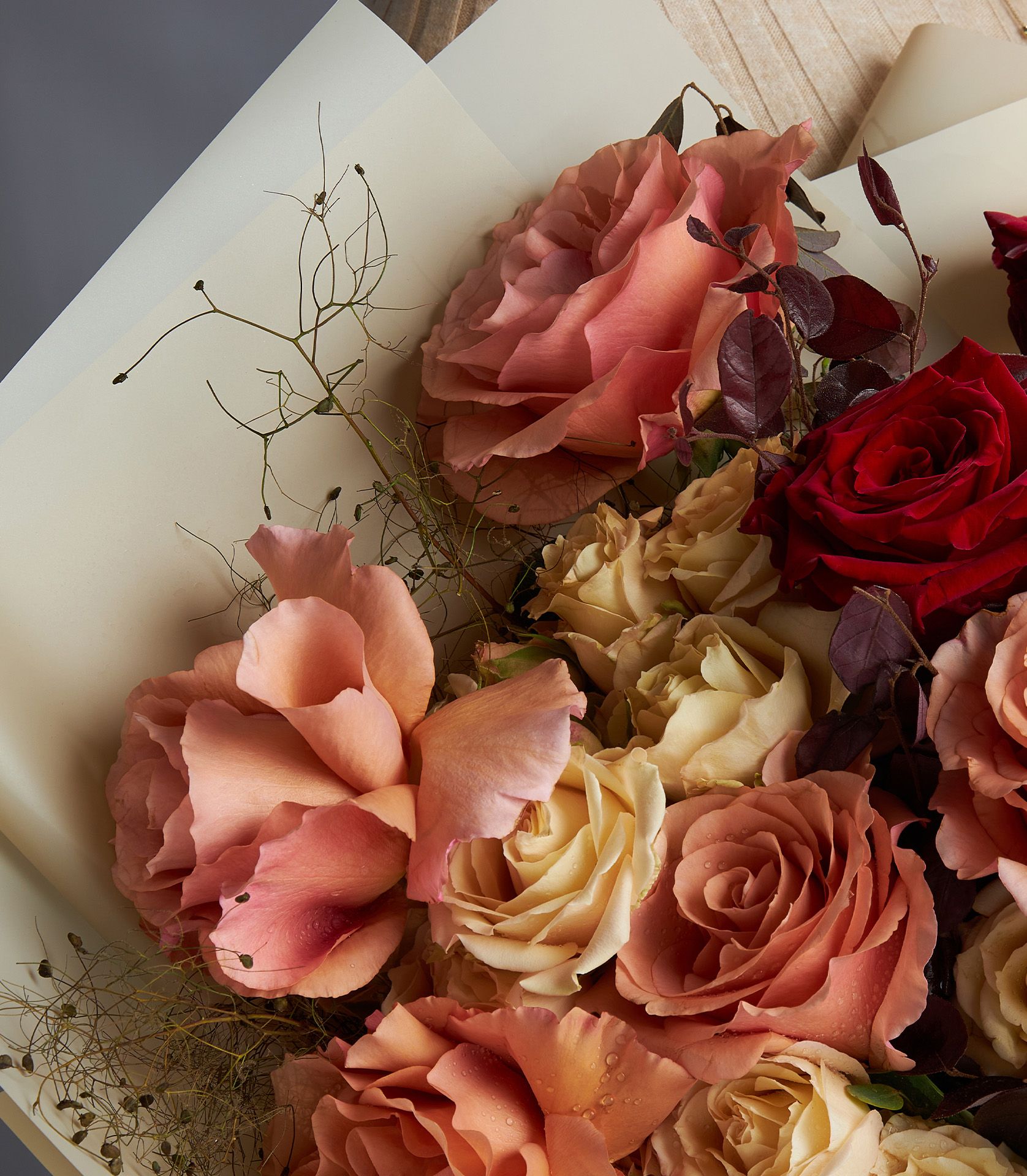 A luxury bouquet of Toffee roses, Explorer red roses, and RP Moab roses, accented with spray roses and eucalyptus, wrapped in soft cream paper.