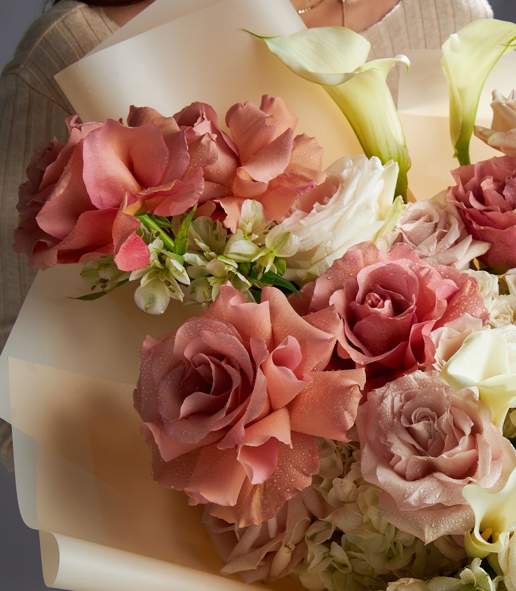 A luxury bouquet of blush, cream, and soft pink imported roses with white calla lilies and elegant wrapping.