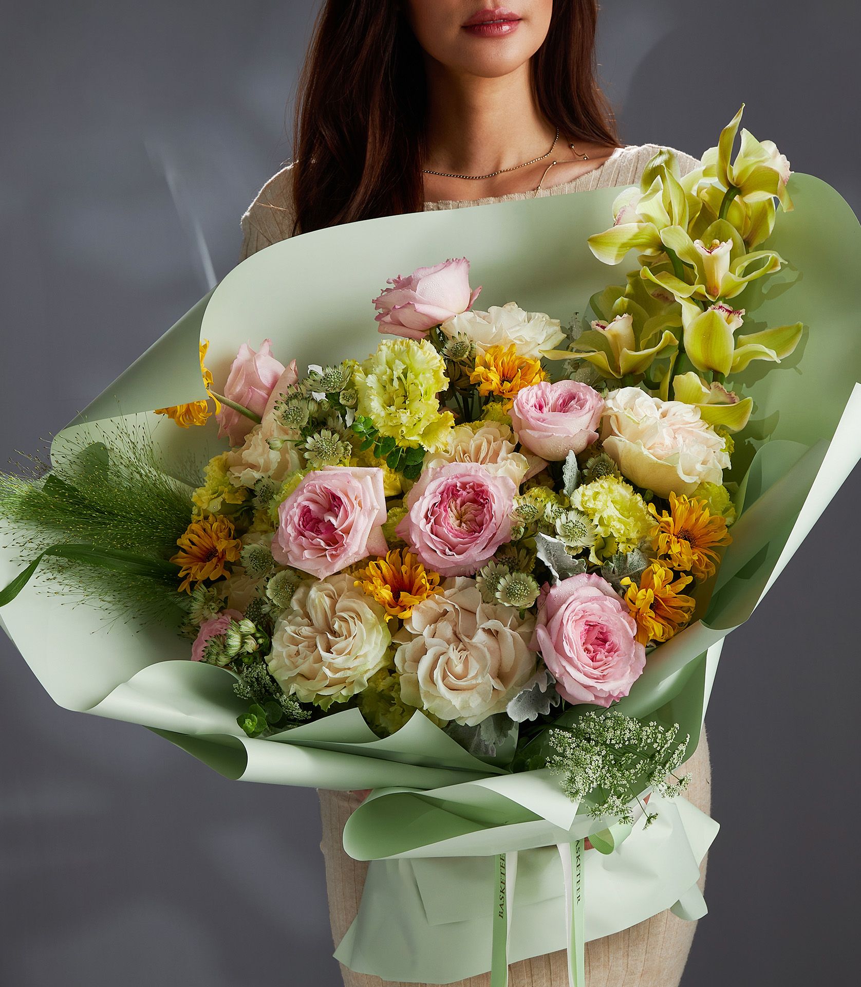 A luxurious bouquet of Keira garden roses, Cotton Xpression roses, green cymbidium orchids, gerberas, lisianthus, and Ammi Majus flowers.
