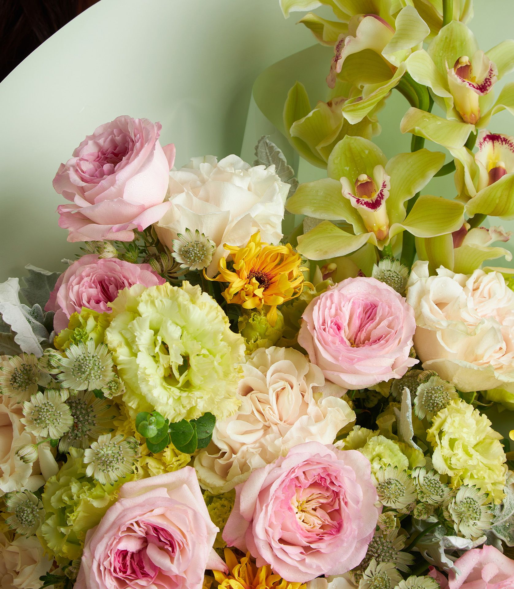 Pastel floral bouquet with Keira roses, Cotton Xpression roses, green cymbidium orchids, yellow gerberas, and green lisianthus.