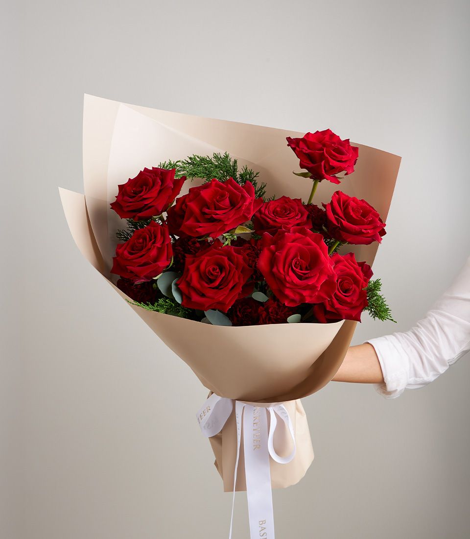 Elegant bouquet of premium red roses imported from Ecuador, wrapped in beige paper with a white ribbon.