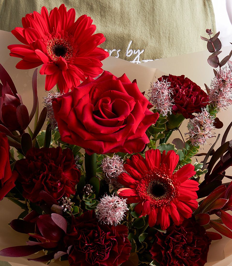 Elegant bouquet of 6 premium red roses with fresh green foliage, wrapped in white paper.