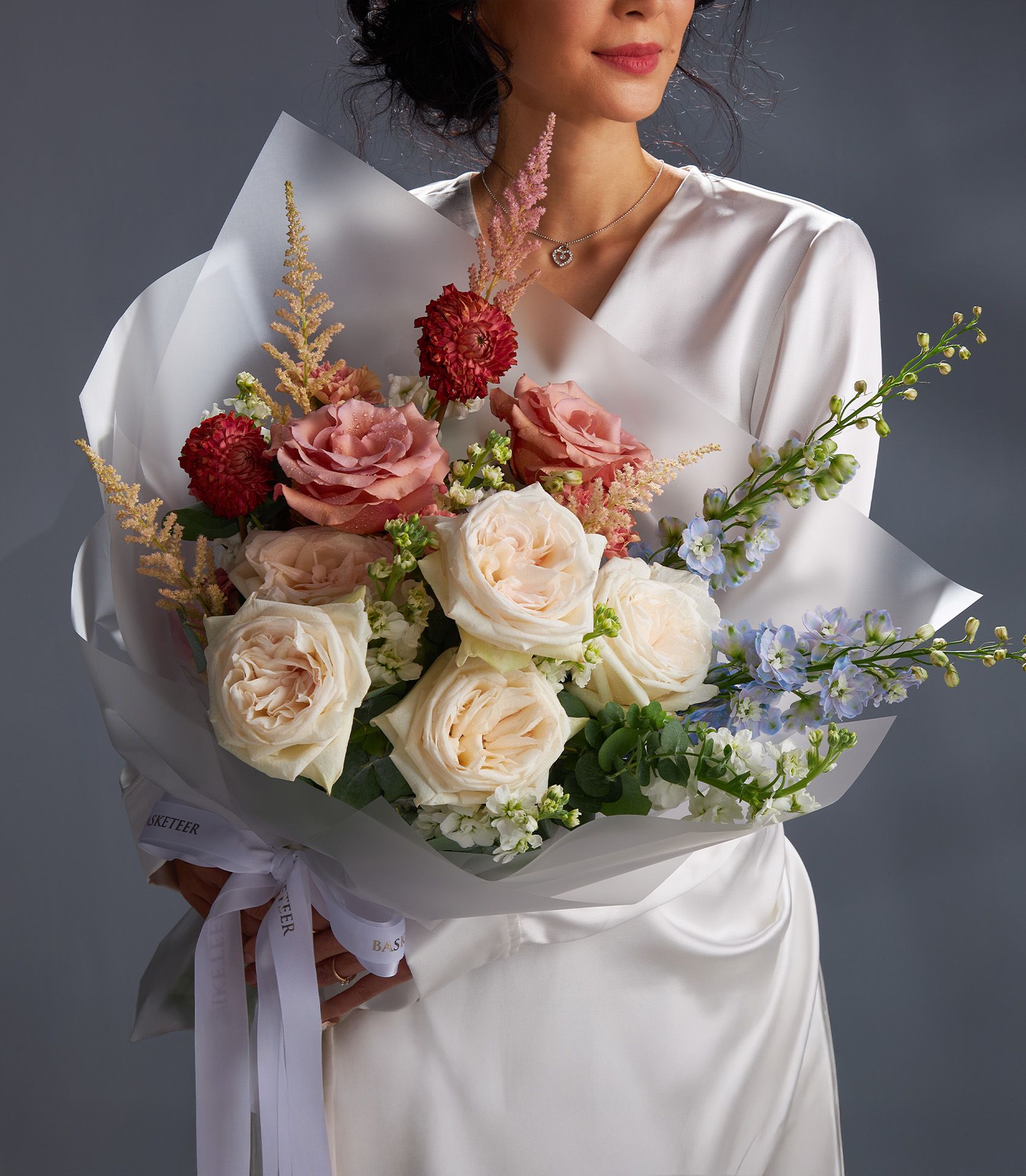 Luxury bouquet of White O’Hara roses and RP Moab roses with red dahlias, blue delphinium, astilbe, eucalyptus, and stock flowers