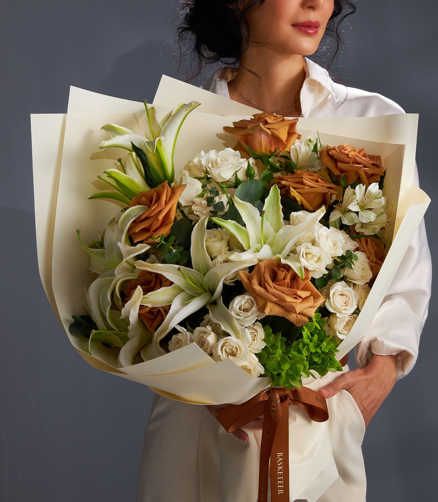 Elegant bouquet with Ecuadorian Toffee roses, white lilies, Majolica spray roses, white alstroemeria, green hydrangeas, and eucalyptus.