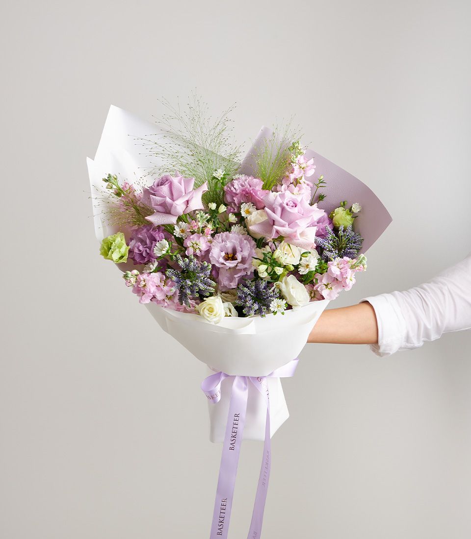 Pastel bouquet of lavender roses, white roses, lisianthus, daisies, and veronica with soft greenery.