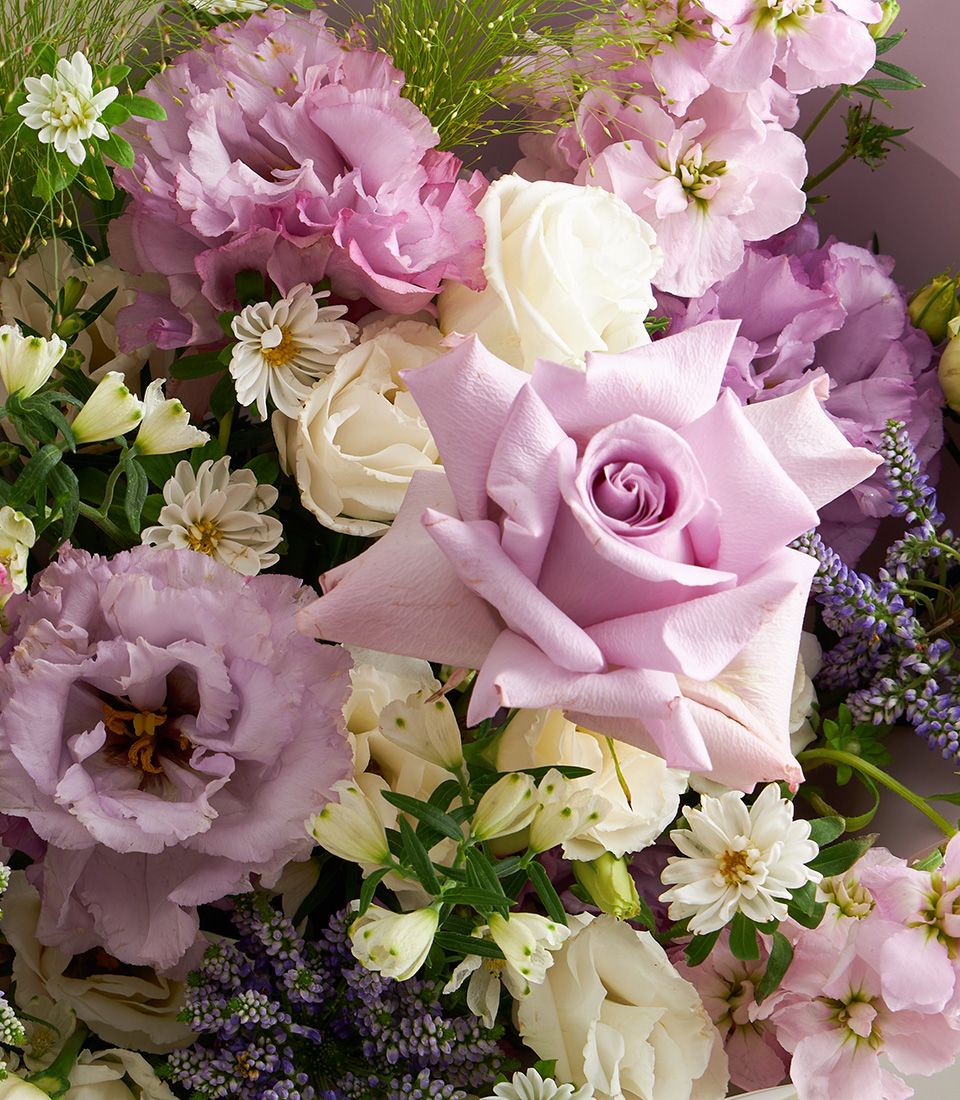 Elegant bouquet of lavender roses, white roses, lisianthus, veronica, and daisies with soft greenery.