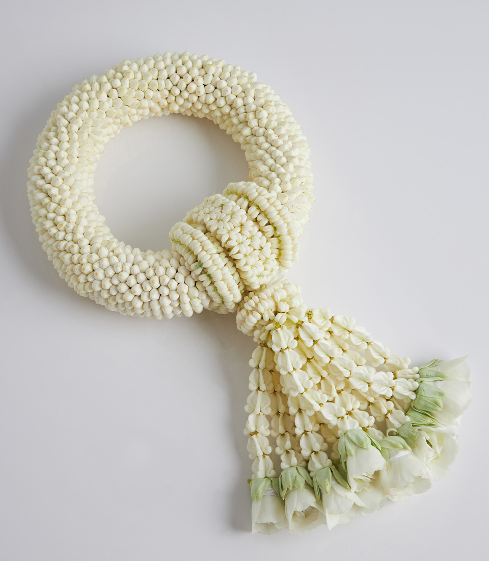 Fresh jasmine garland with white rosebuds, intricately handwoven in a circular design with floral tassels.