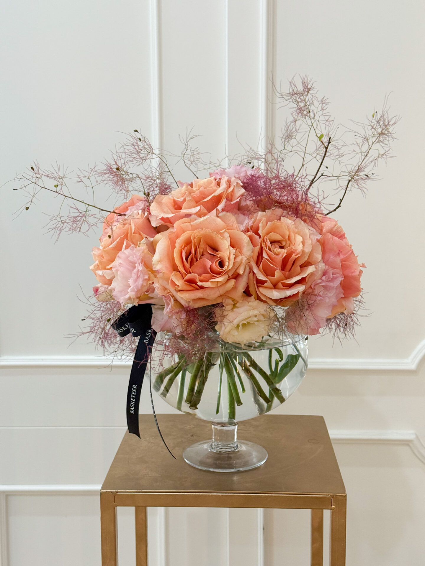 Elegant vase with peach roses, pink lisianthus, and soft smoky accents tied with a Basketeer ribbon.