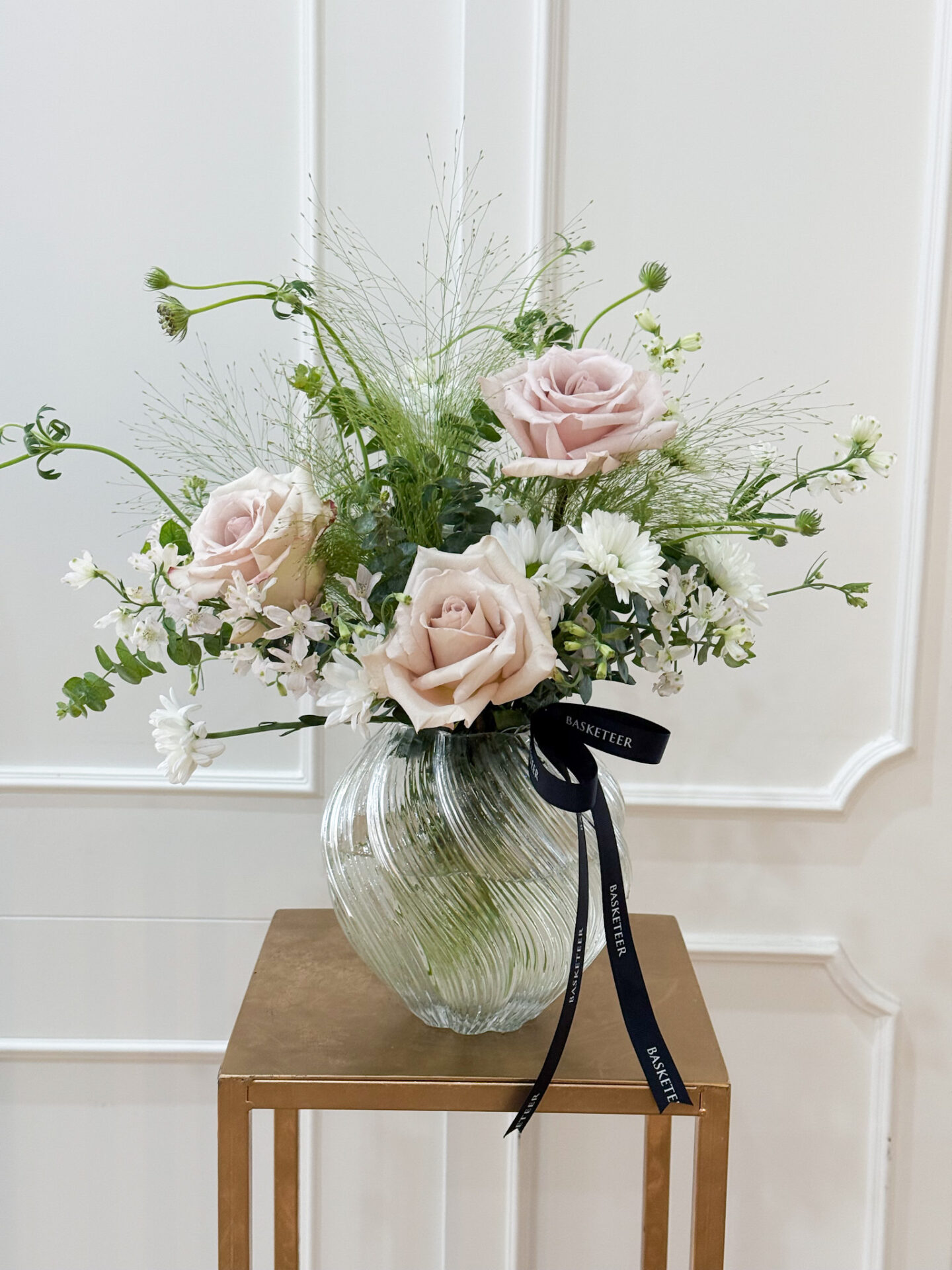Elegant vase with pastel nude roses, white chrysanthemums, and greenery, tied with Basketeer ribbon.