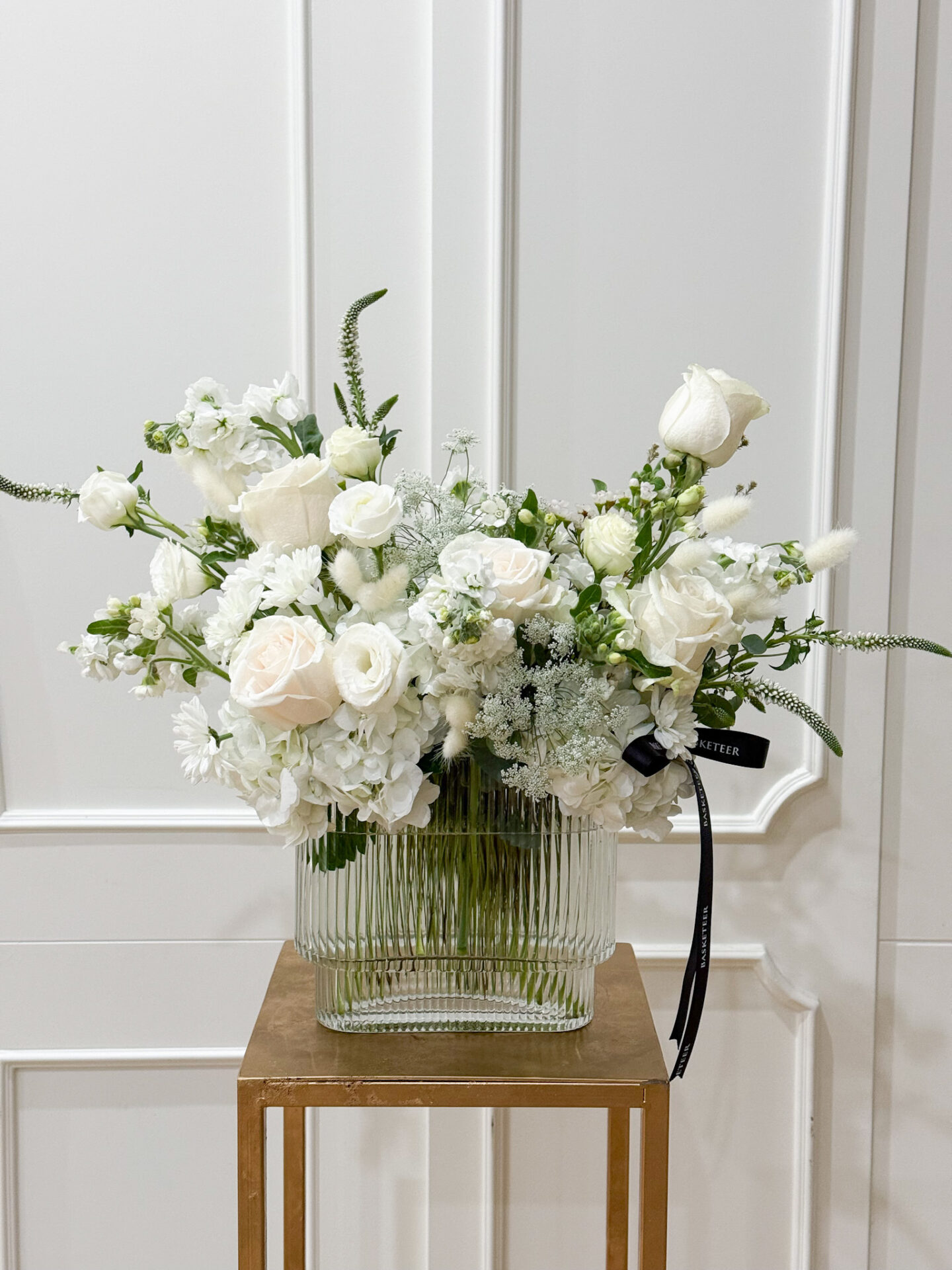 Glass vase with white roses, hydrangeas, lisianthus, and seasonal fillers in a pure and elegant style.