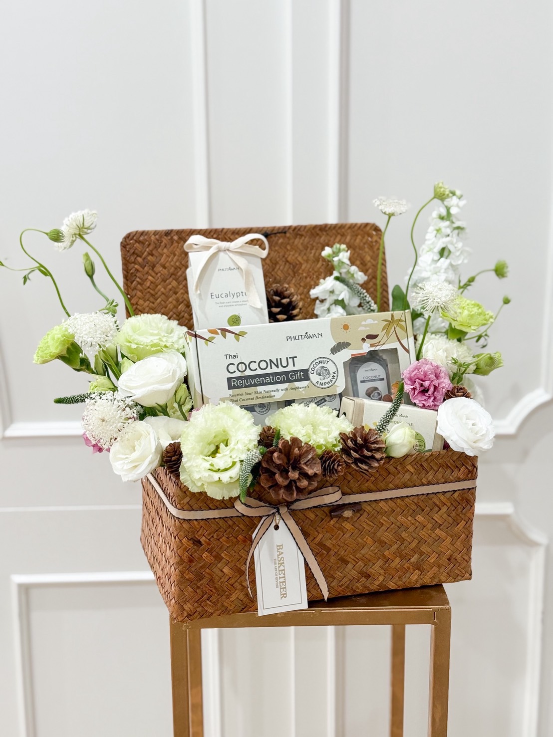 Elegant spa gift basket in white and green tones, featuring Thai herbal coconut set, eucalyptus products, and fresh flowers.