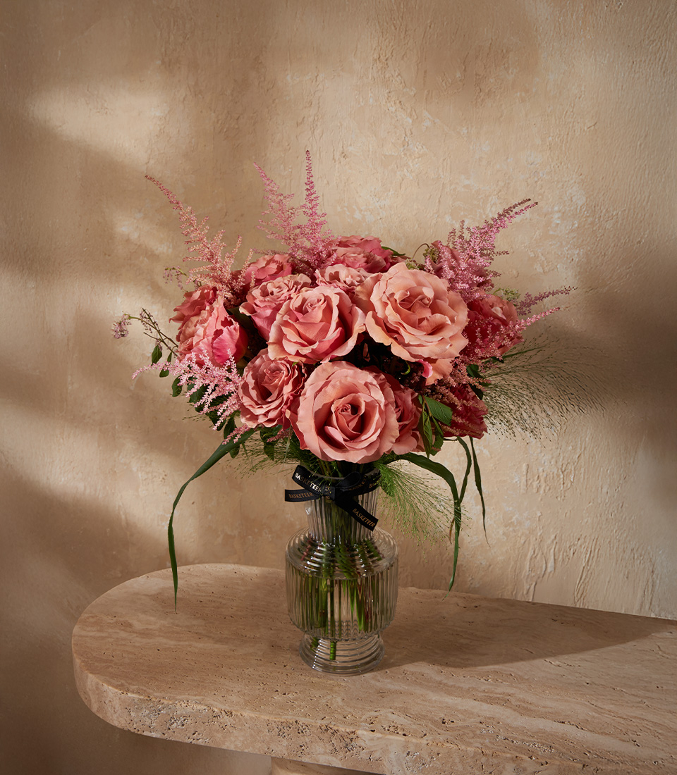 Luxury vase arrangement with premium pink roses and astilbe in deep blush tones, styled with greenery for an elegant look.