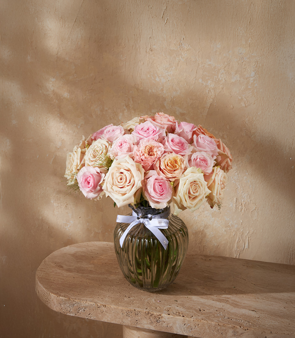Elegant flower arrangement with pastel pink and cream roses in a glass vase