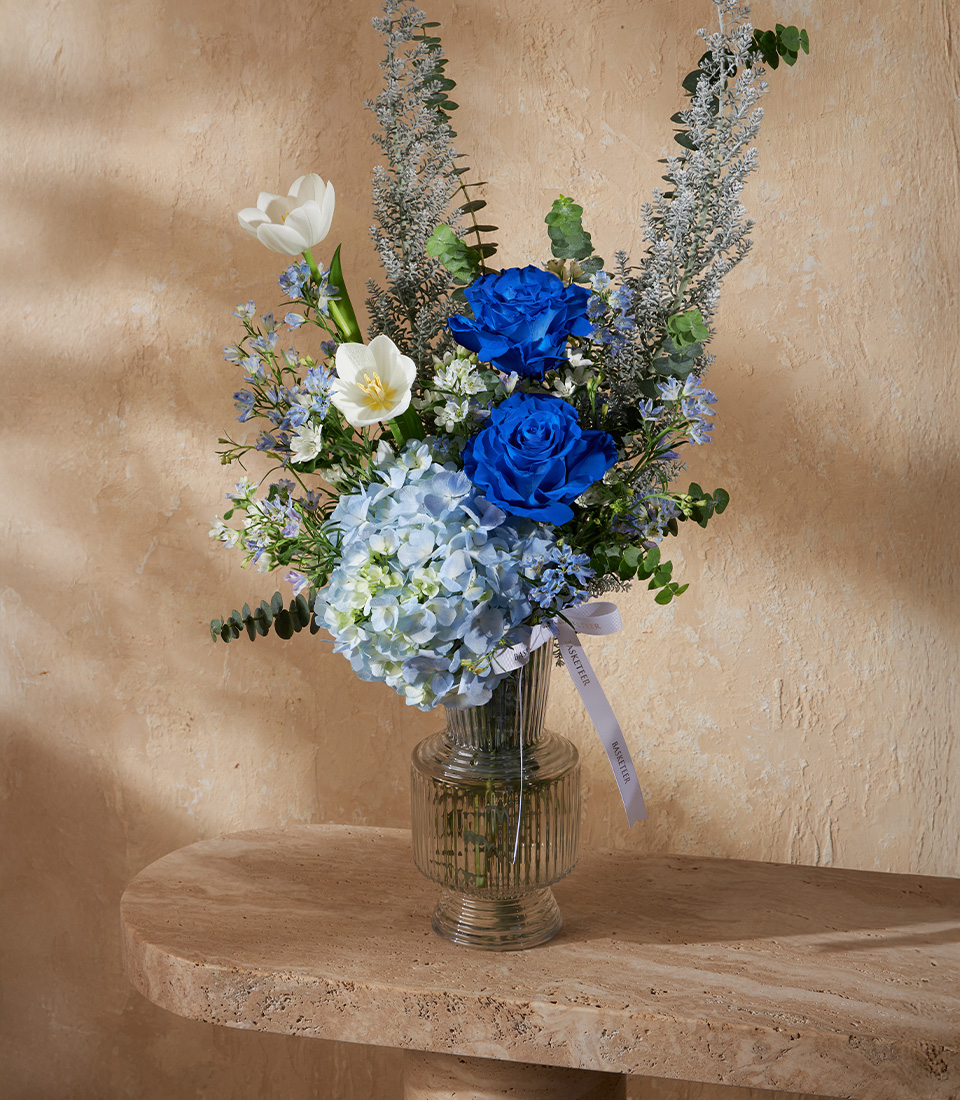 Luxury flower arrangement with blue roses, white tulips, and hydrangeas in a tall glass vase, perfect for premium gifts and Bangkok flower delivery.