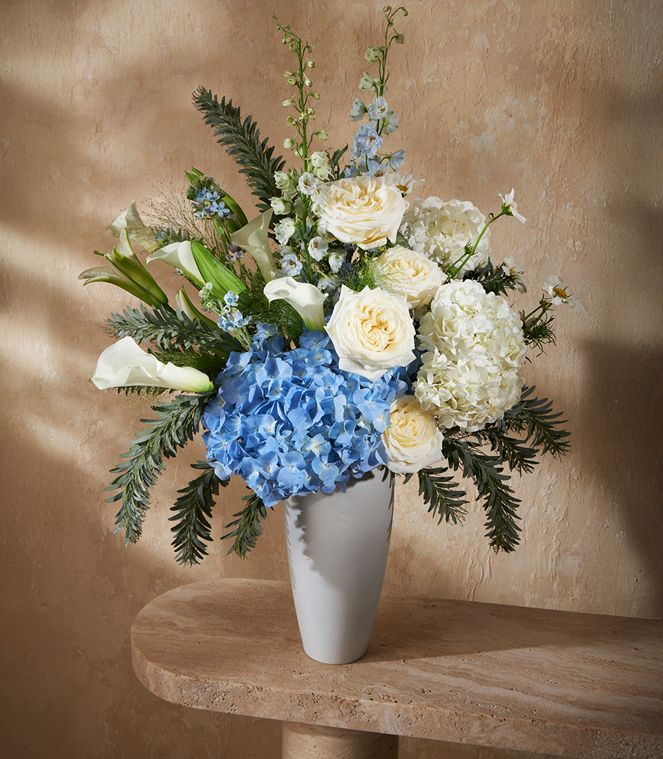 Luxury flower arrangement with blue hydrangeas, white roses, and calla lilies in an elegant vase, perfect for Bangkok flower delivery.