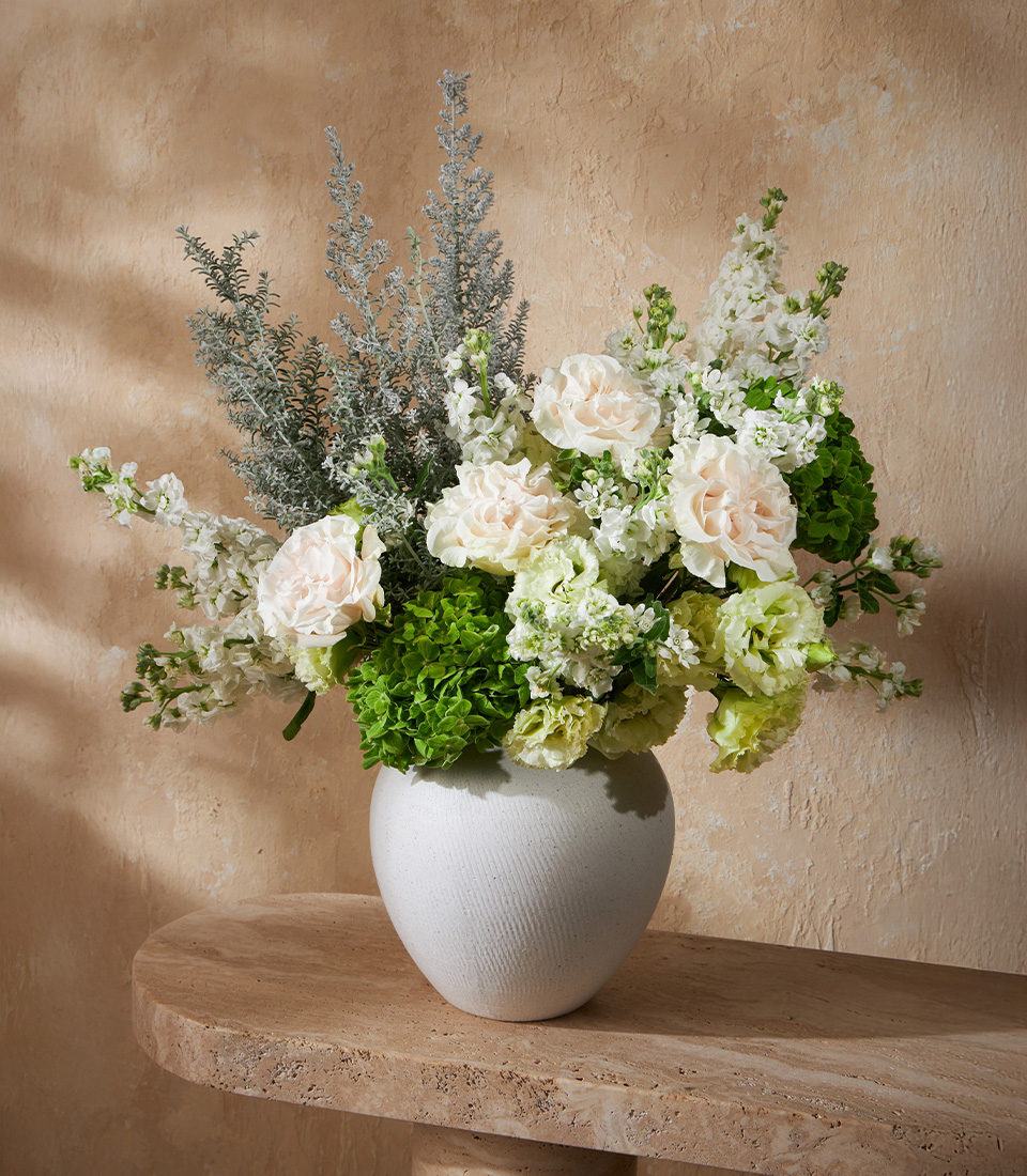 Elegant flower arrangement with white roses, green hydrangeas, and stock flowers in a modern vase, perfect for Bangkok flower delivery.