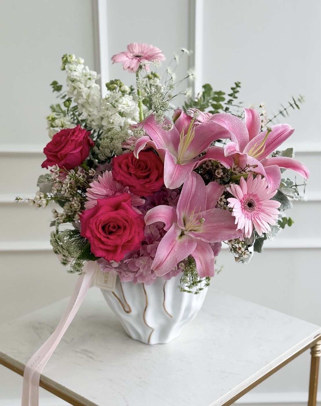 Luxury vase with pink lilies, red roses, pink gerberas, and hydrangeas, accented with white blooms and greenery