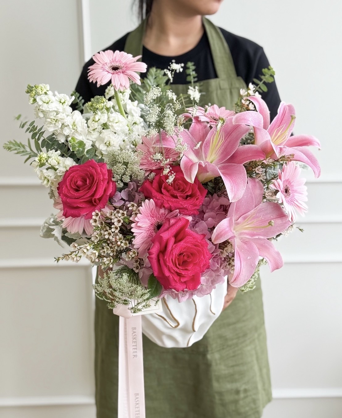 Vase with pink lilies, hot pink roses, pastel gerberas, hydrangeas, white flowers, and fresh greenery