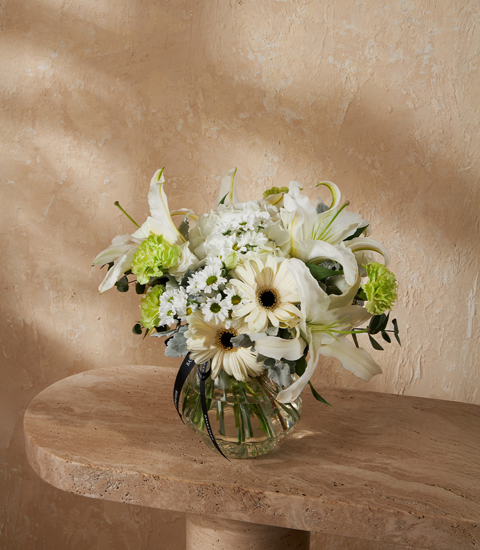 Flower vase arrangement with white lilies gerberas green carnations and seasonal blooms in a round vase