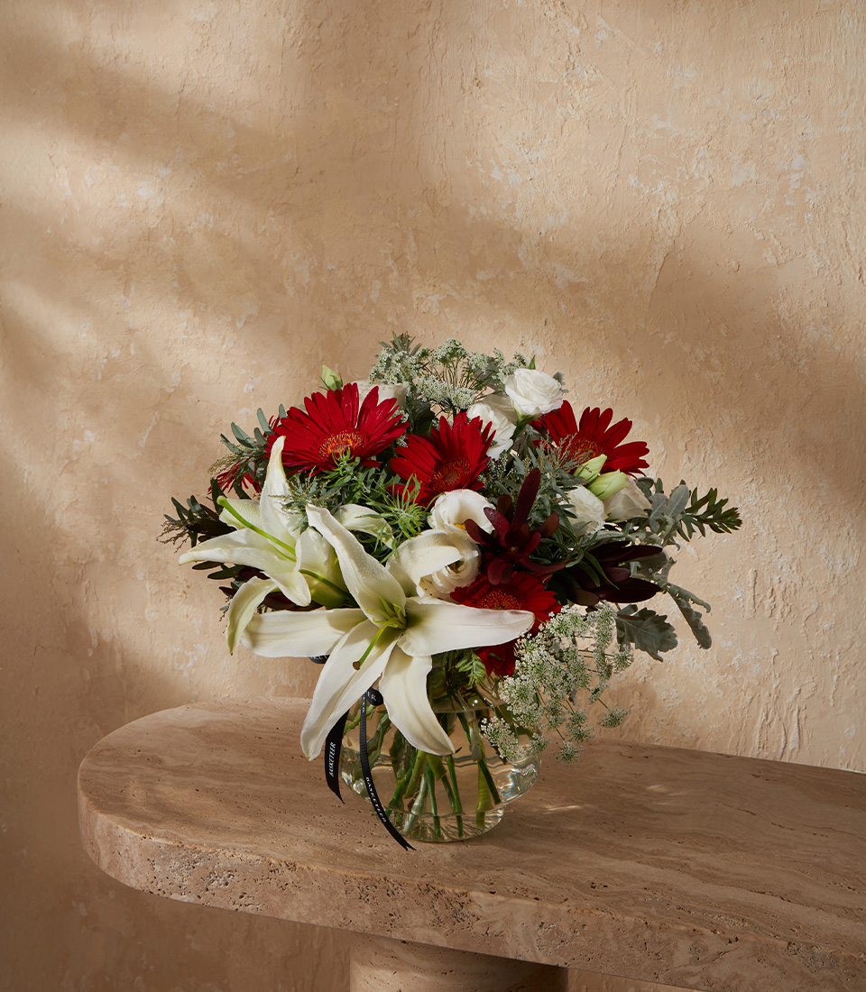 Flower vase arrangement with white lilies and red gerberas in elegant design