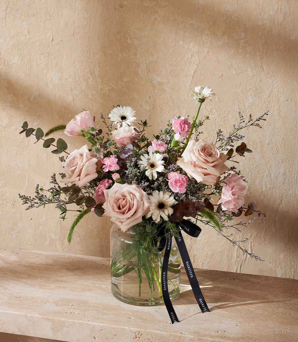 Flower vase with blush roses pink carnations and white gerberas arranged with eucalyptus in a clear glass vase Romantic pastel bouquet delivery in Bangkok