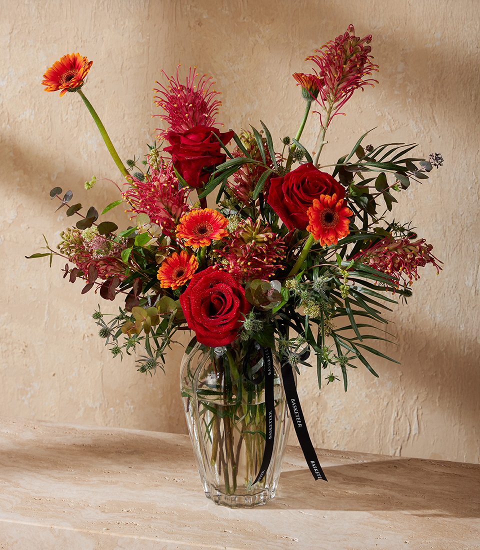Vase with red roses orange gerberas and tropical flowers Elegant bold floral arrangement for celebrations anniversaries and flower delivery in Bangkok