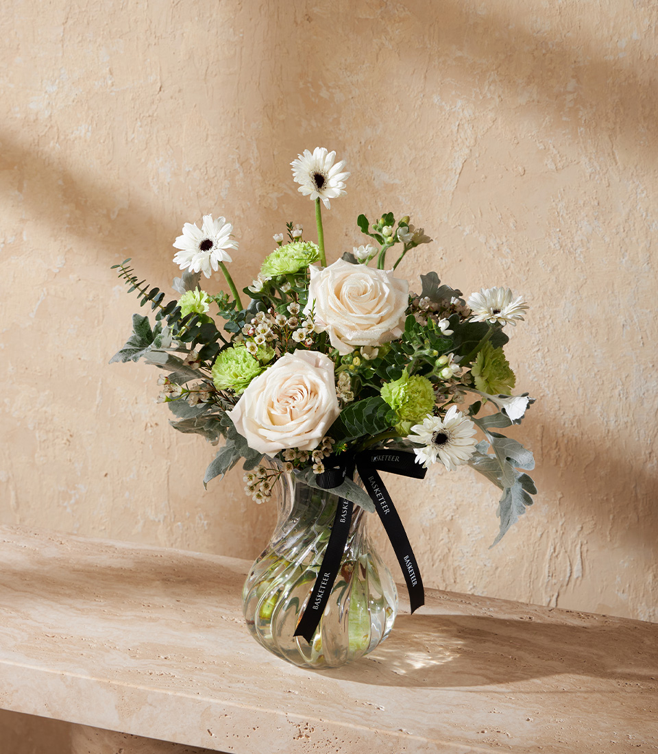Flower vase arrangement with white roses green carnations gerberas and lush greenery in a clear glass vase Elegant floral gift delivery in Bangkok