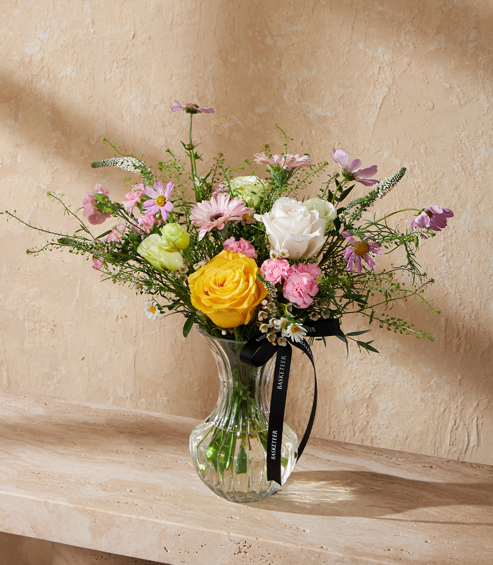 Flower vase arrangement with yellow roses white roses pink carnations and purple cosmos in a clear glass vase Bright cheerful bouquet delivery in Bangkok