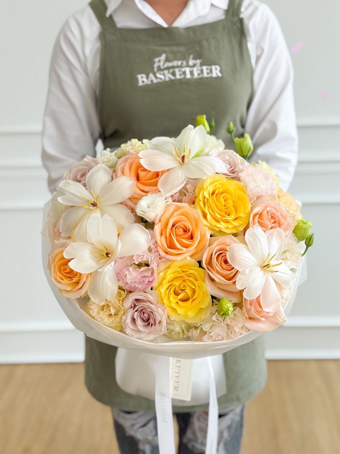 A person wearing a green apron that reads 
