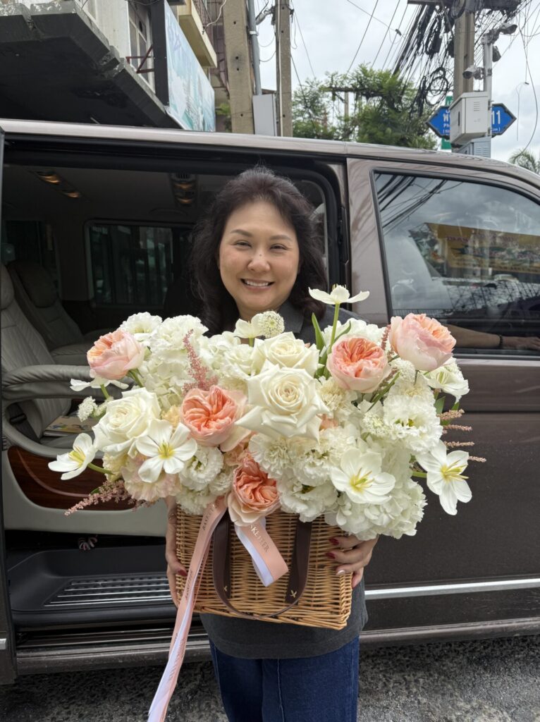 Woman holding a white and peach flower basket from Flowers by Basketeer