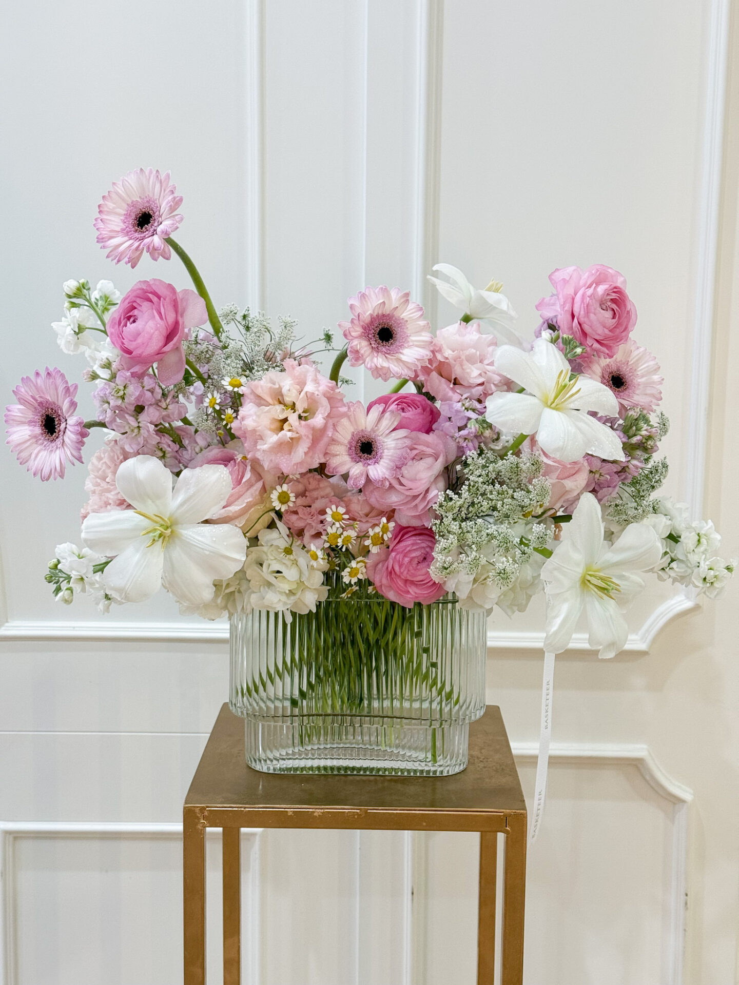 Elegant vase with pink ranunculus, gerberas, lisianthus, white lilies, and seasonal fillers arranged in soft romantic tones.