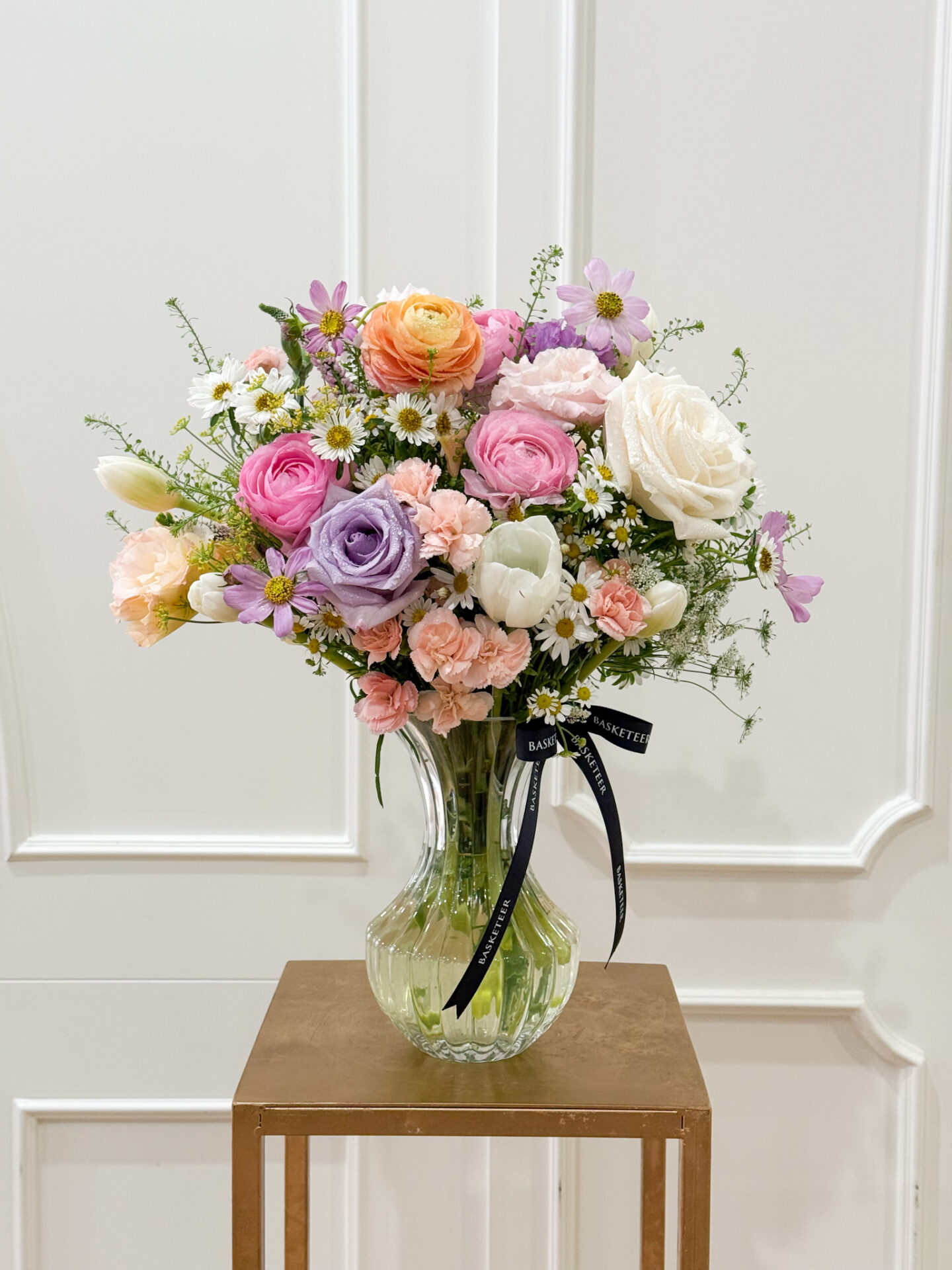 Luxury vase with pastel roses, ranunculus, carnations, tulips, cosmos, and chamomile in soft pink, purple, orange, and white tones.
