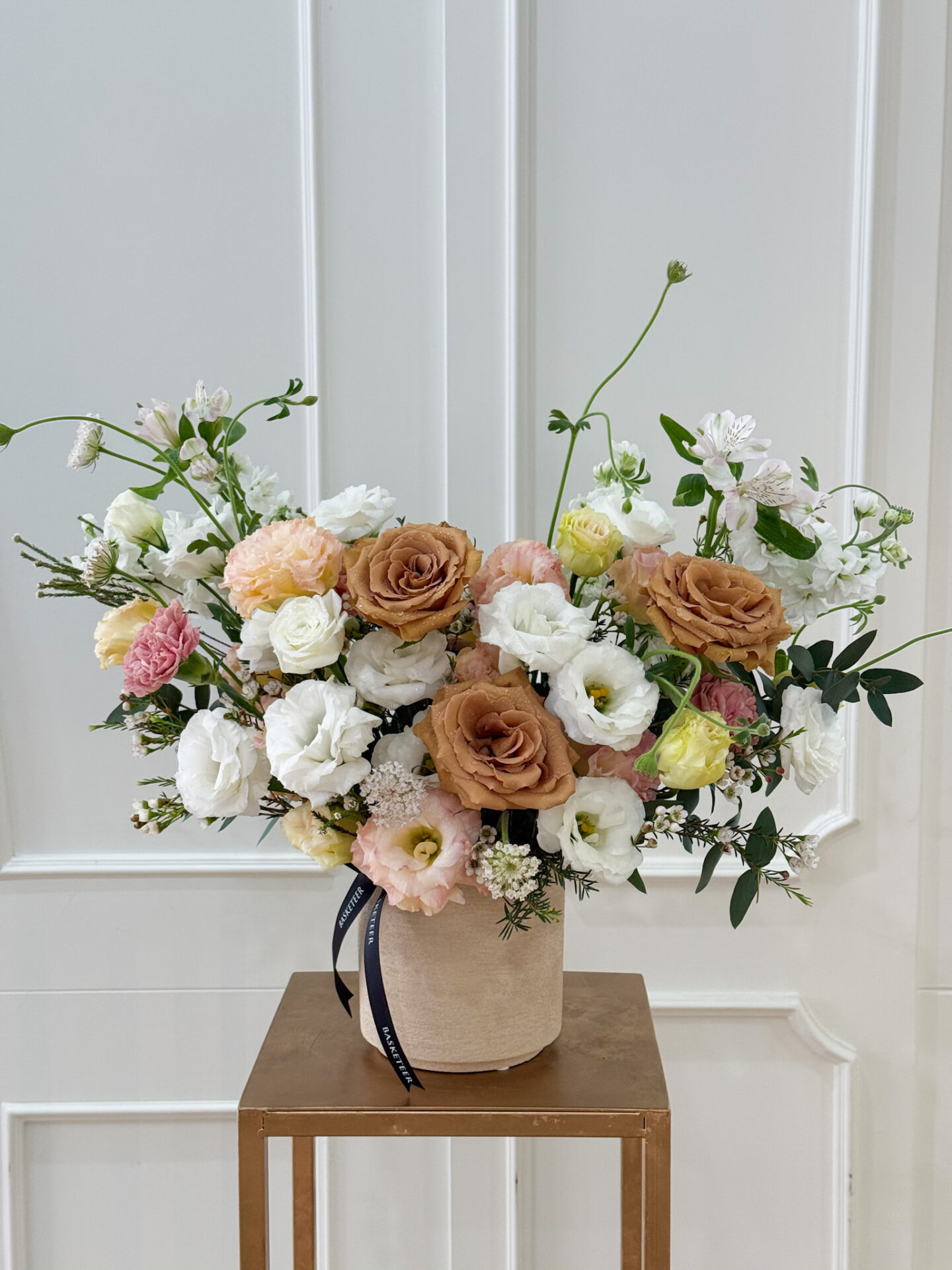 Elegant vase with caramel roses, white lisianthus, peach ranunculus, and pastel blooms for a refined floral arrangement.