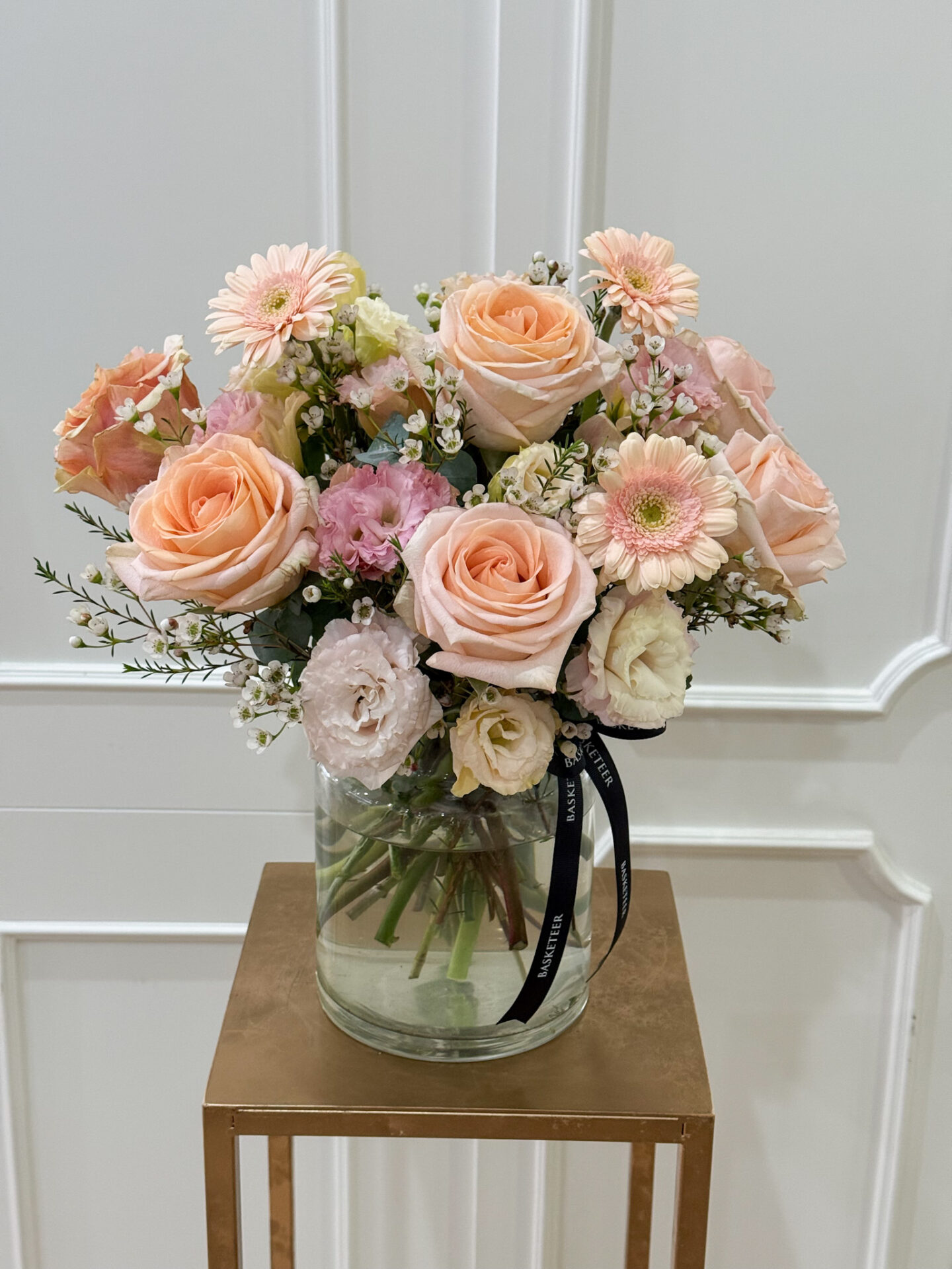Elegant vase arrangement with peach roses, soft pink gerberas, lisianthus, and delicate filler flowers.