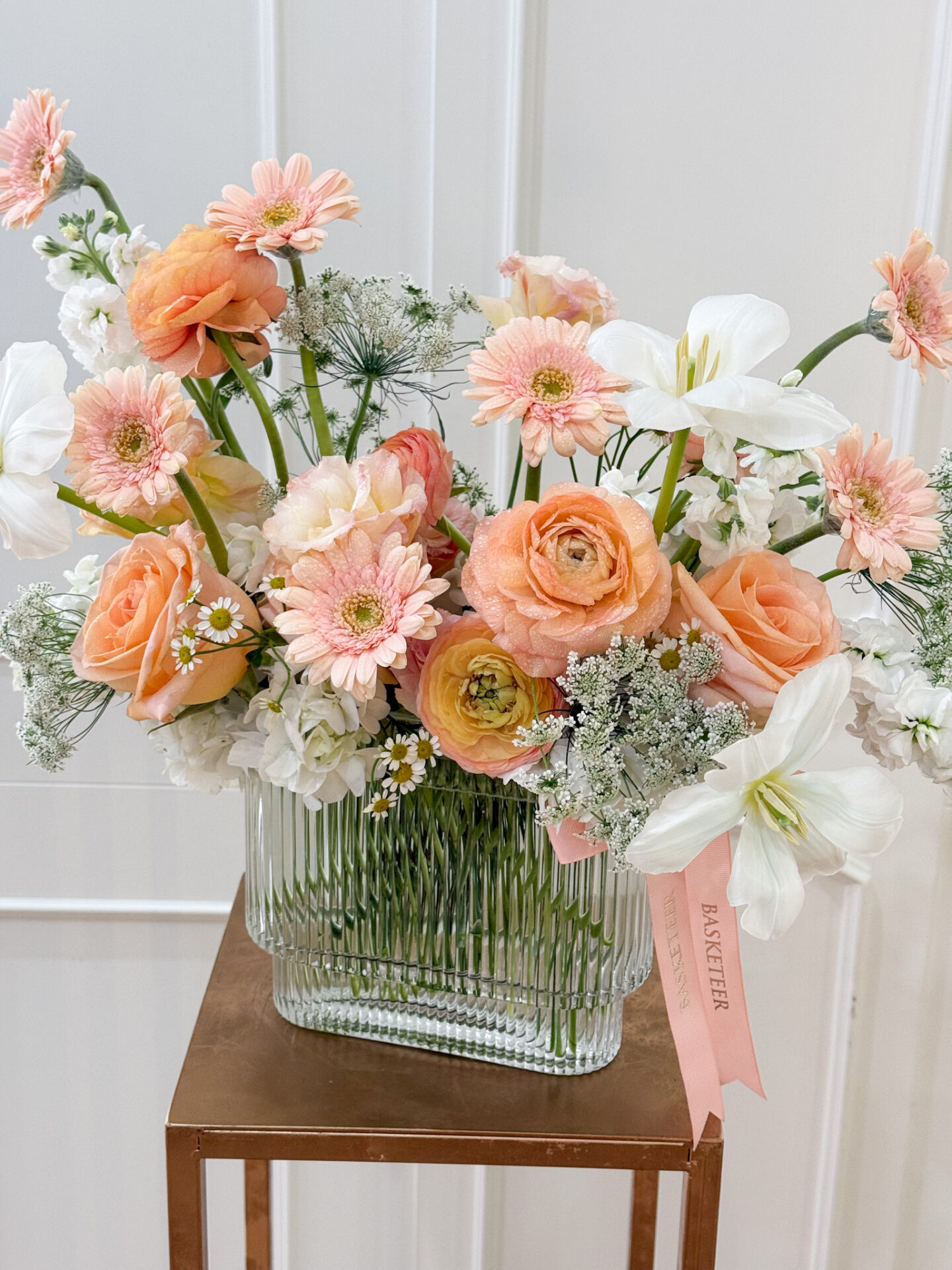 Luxury vase with peach roses, ranunculus, white lilies, peach gerberas, and pastel fillers in a clear glass vase.