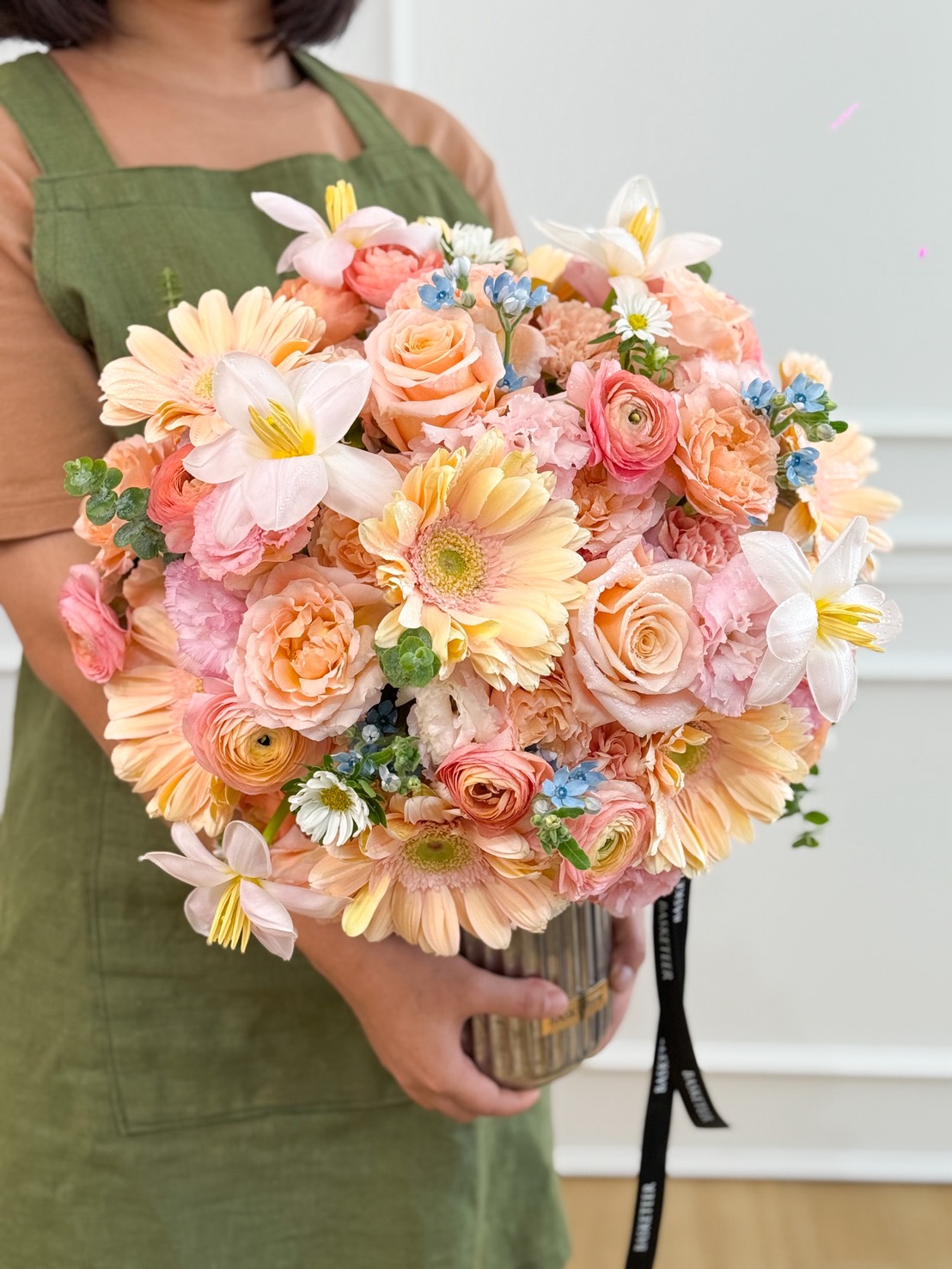 Pastel peach and pink flower bouquet featuring roses, gerberas, and mixed blooms in a glass vase.