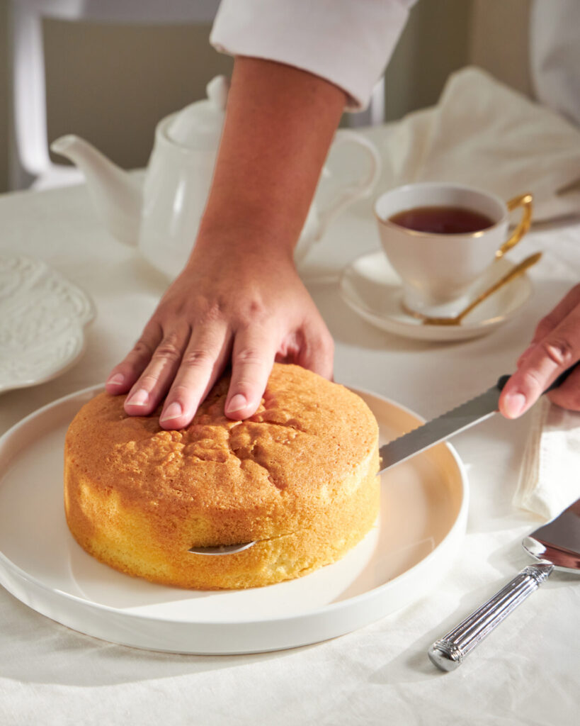 Baker from Charlotte Bakery Bangkok slicing a sponge cake layer