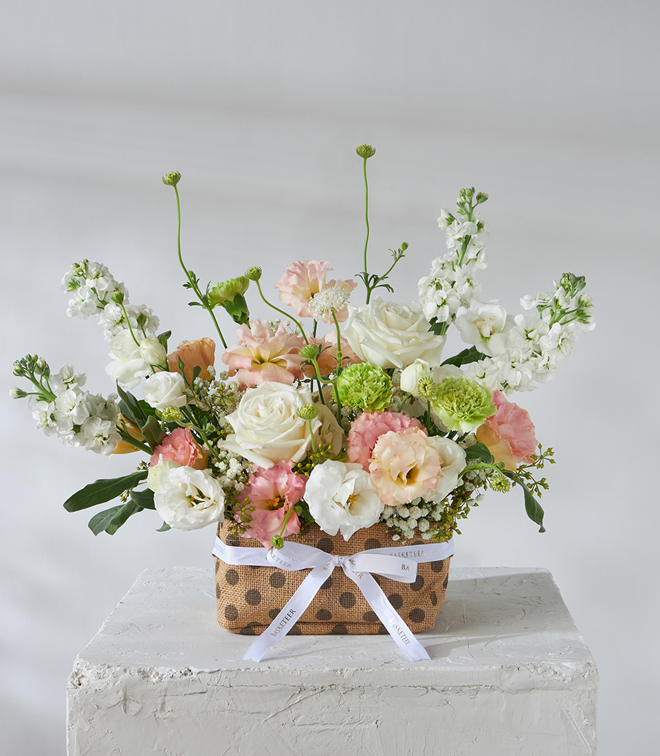 Front view of basket with white roses and peach lisianthus.