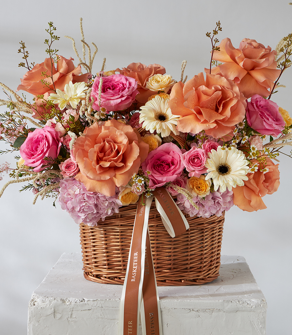 Front view of orange and pink rose basket bouquet with gerbera daisies.