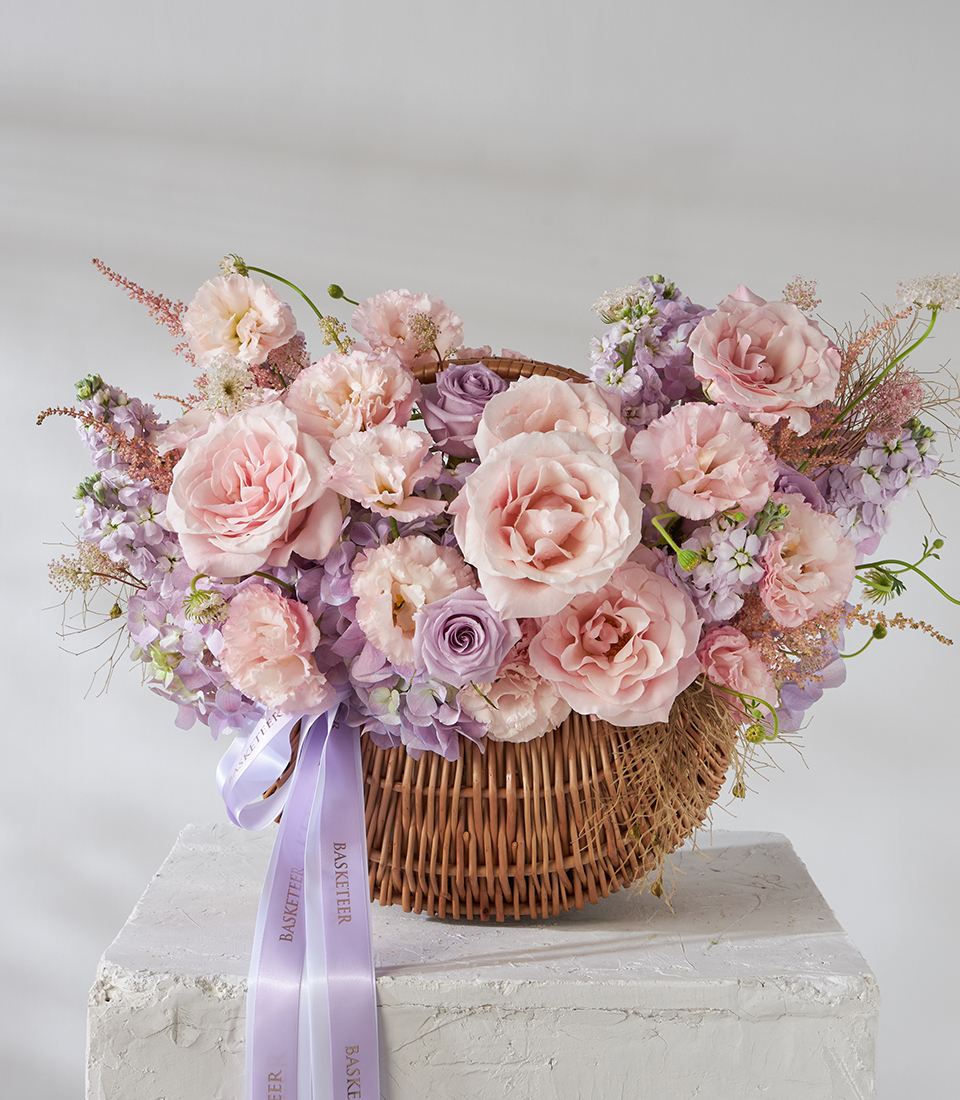 Front view of blush pink rose and purple lisianthus basket bouquet.