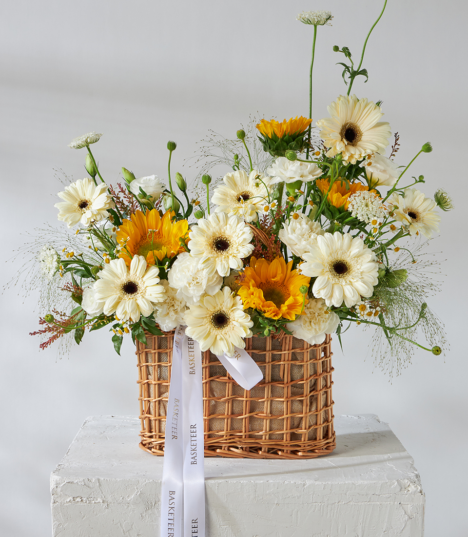 Front view of basket bouquet with sunflowers and white gerbera daisies.
