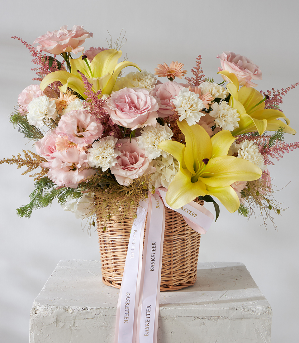 Front view of yellow lily and pink rose basket bouquet.